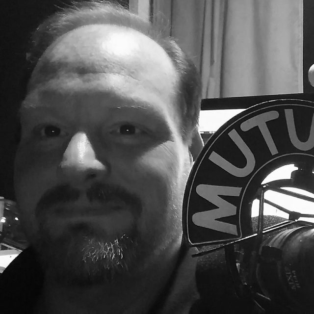 Leo Ashcraft at the microphone, black and white